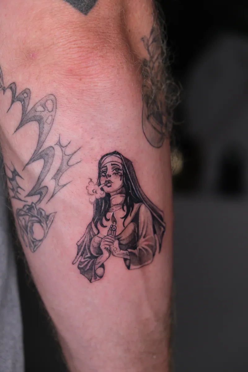 Kleines figürliches Tattoo am Oberarm