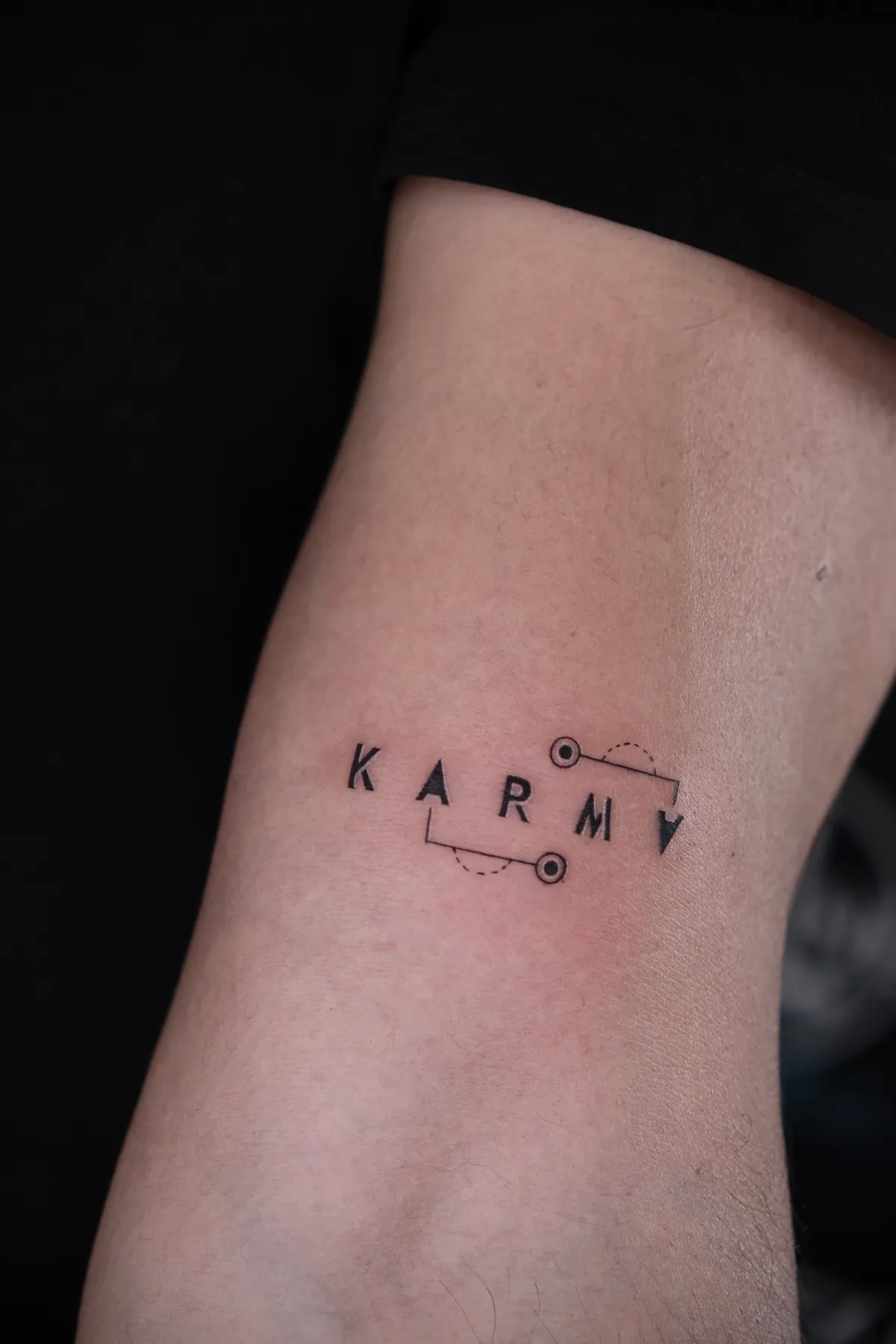 Geometrischer Schriftzug Karma am Unterarm