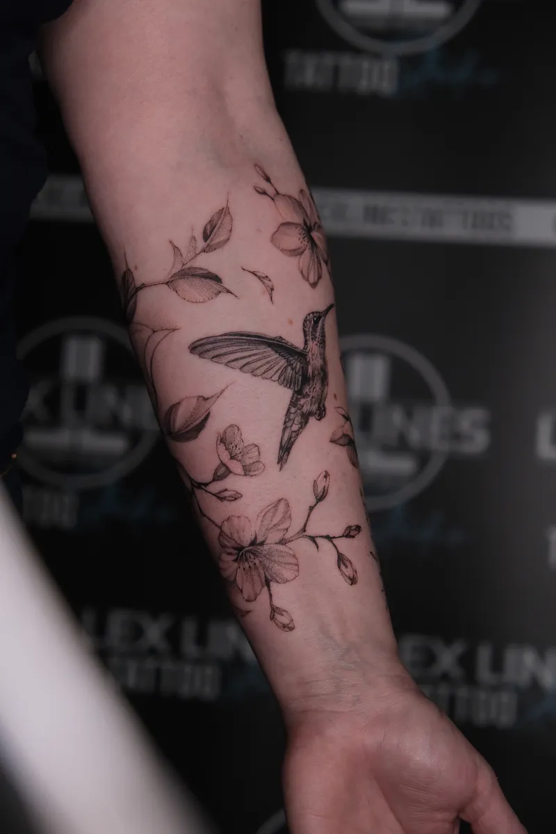 Kolibri zwischen Blüten am Unterarm